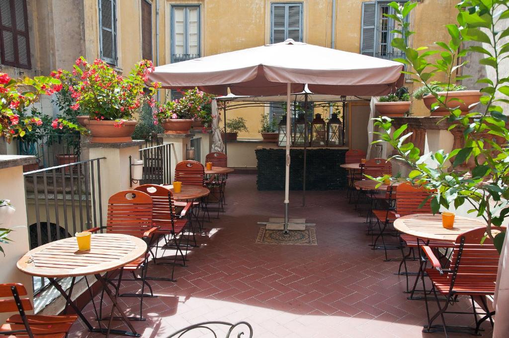 a patio with tables and chairs and an umbrella at Hotel Le Clarisse al Pantheon in Rome