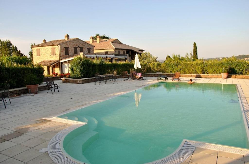 una gran piscina con una casa en el fondo en Villa Bice, en Tolentino