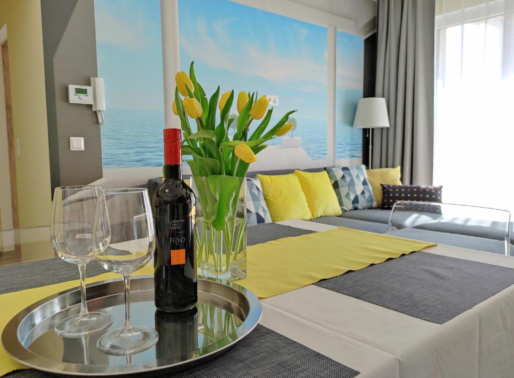 NEST2 Apartments في كيزتيلي: طاولة مع زجاجة من النبيذ وكأسين من النبيذ