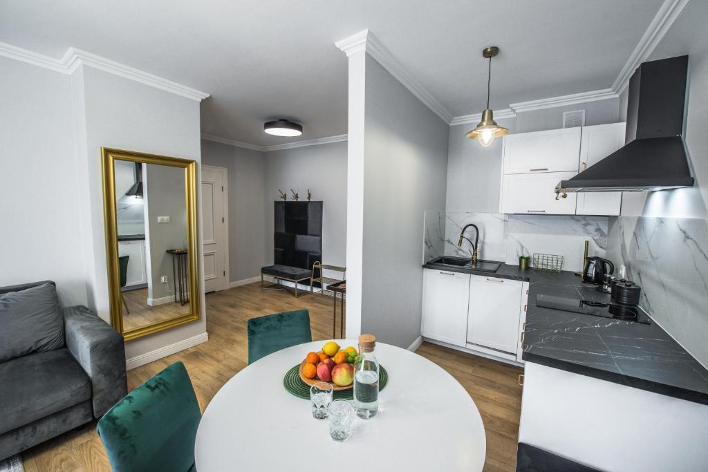 a kitchen and living room with a table with fruit on it at Słone Residence Apartamenty & Beer SPA in Kudowa-Zdrój