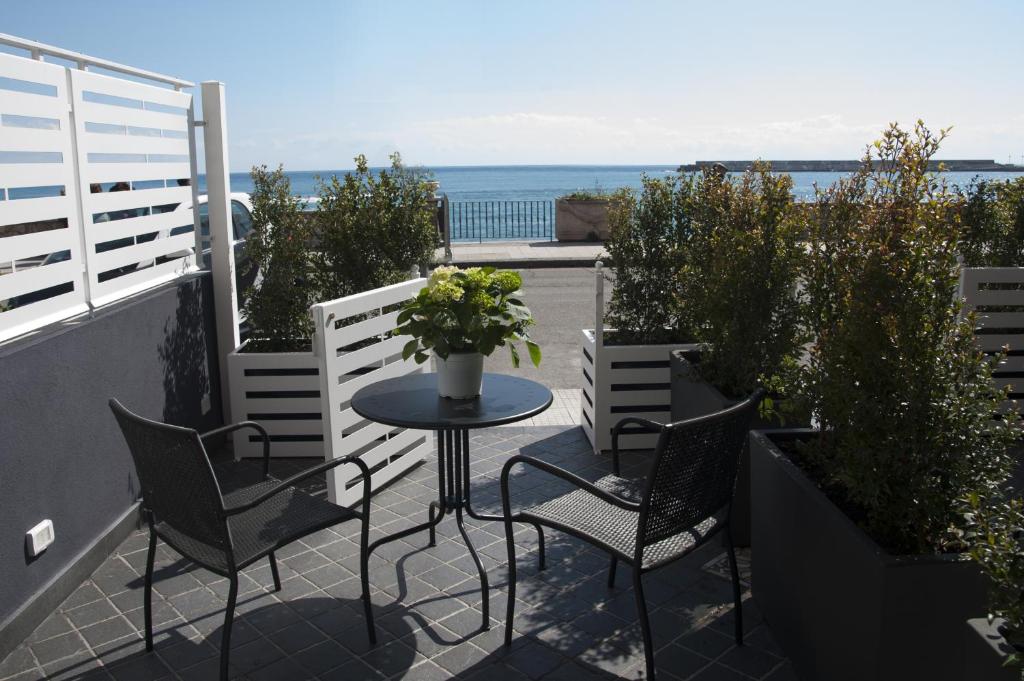 una mesa y sillas en un balcón con vistas al océano en AG Luxury Rooms, en Giardini Naxos