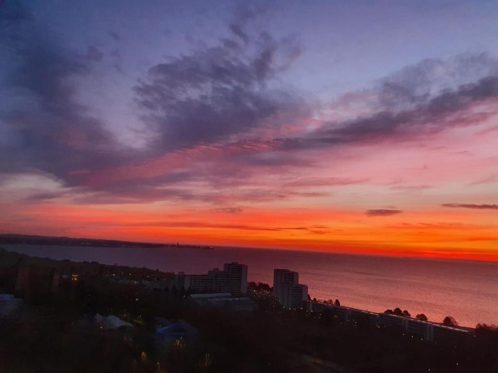 een zonsondergang boven de oceaan met een stad bij Oase mit Meerblick, Schwimmbad & nahe Hansapark in Sierksdorf