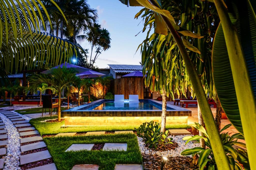 a swimming pool in a resort with palm trees at Pousada Boutique Coco Bambu Morere in Moreré