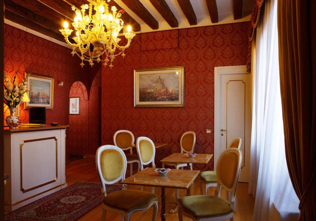 ein Esszimmer mit roten Wänden sowie einem Tisch und Stühlen in der Unterkunft Locanda Correr in Venedig