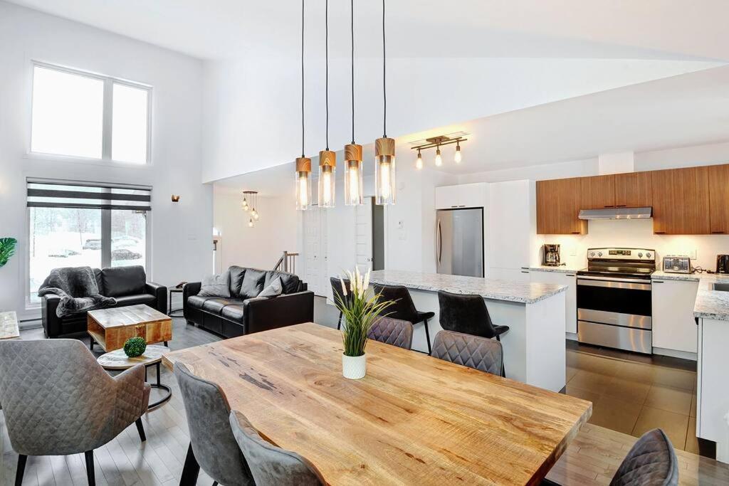 a kitchen and living room with a table and chairs at 05 Chemin des Cascades in Stoneham