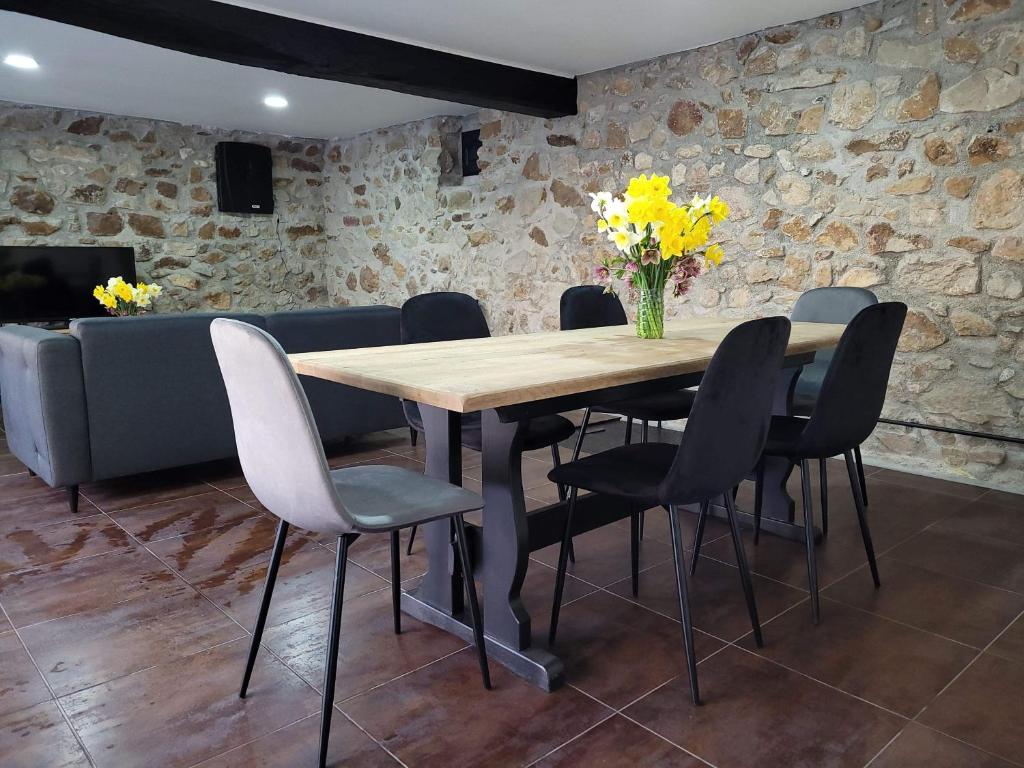 uma mesa de madeira com cadeiras e um vaso de flores amarelas em Maison de caractère em Crancey