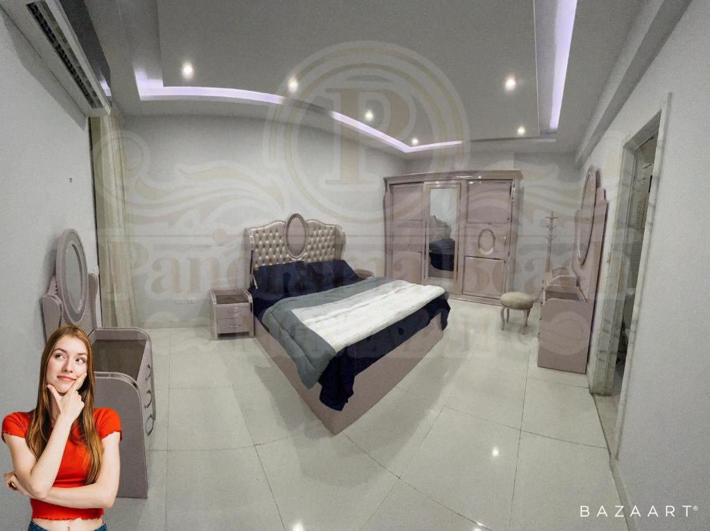 een vrouw die voor een slaapkamer met een bed staat bij شقق بانوراما شاطئ الأسكندرية كود 1 in Alexandrië