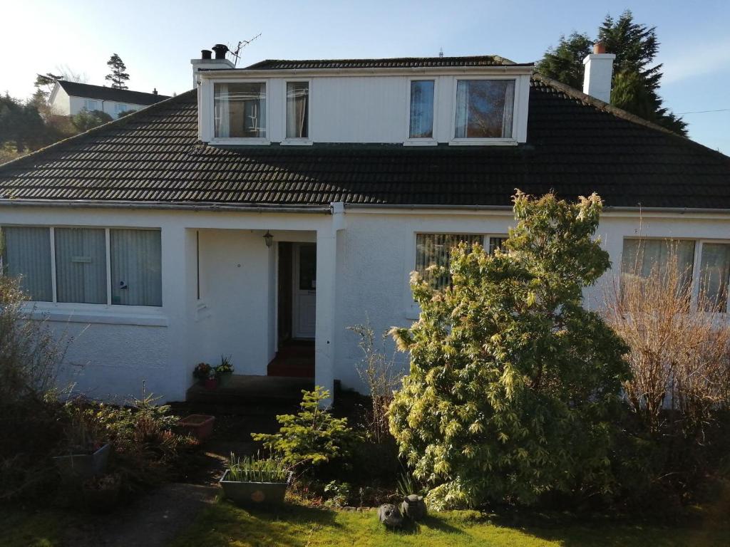 a white house with a tree in the yard at Don Muir Guesthouse in Oban