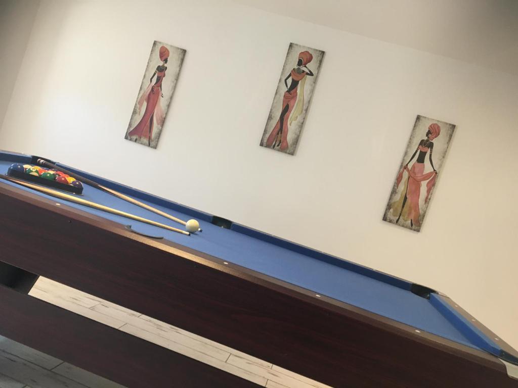 three pictures on a wall above a pool table at Logement détente avec jacuzzi et billard américain in Fournols