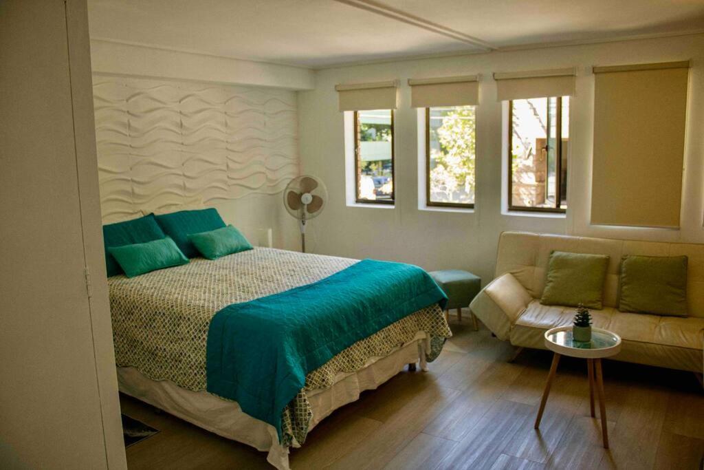 um quarto com uma cama, um sofá e janelas em Departamento mall costanera em Santiago