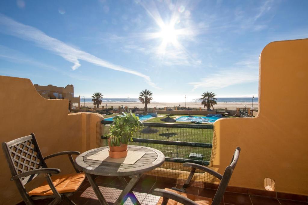 Un balcón con mesa y sillas y vista a la playa. en Los Lances Playa en primera linea, en Tarifa
