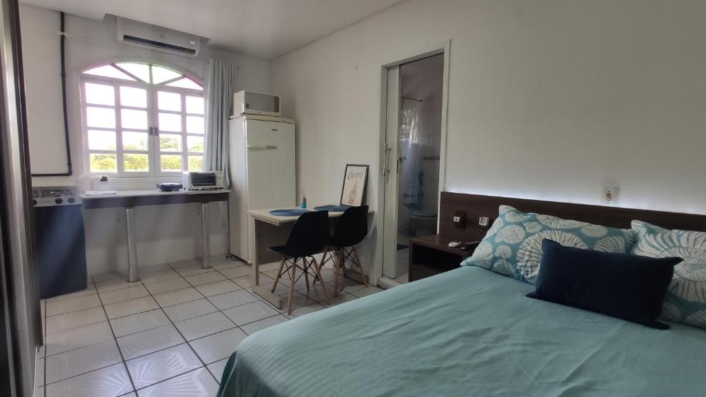Cet appartement comprend une chambre avec un lit vert et une cuisine. dans l'établissement Studio na praça da Lagoa, pertinho de tudo!, à Florianópolis