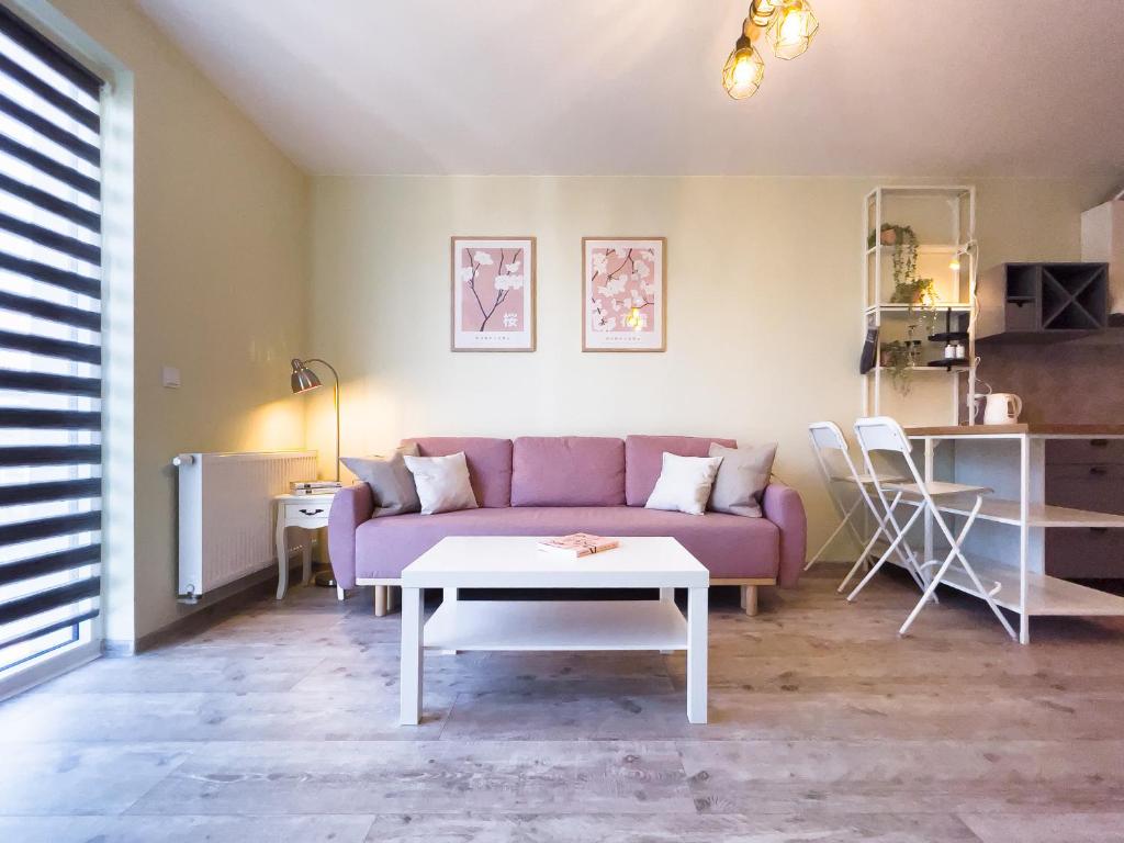 a living room with a purple couch and a table at Bliżej Morza AON Apartament Gdańsk in Gdańsk