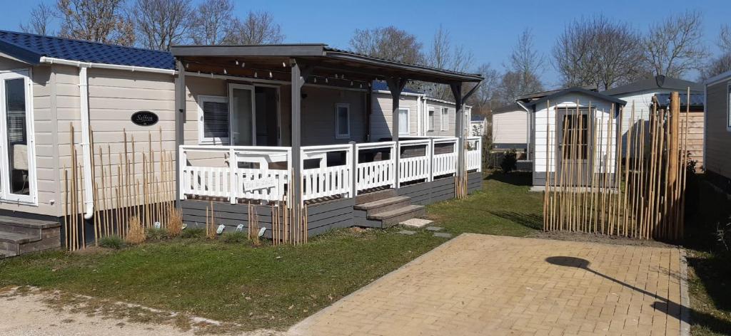 a small house with a porch and a white fence at Zee&Zout, chalet 6 pers. bij Renesse en strand! in Renesse
