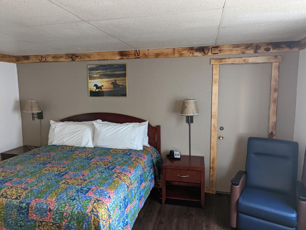 a bedroom with a bed and a blue chair at Wyatt Earp Hotel in Dodge City