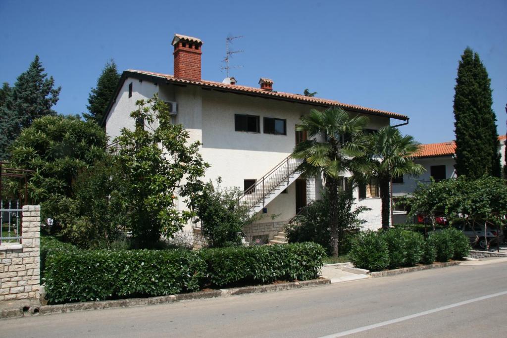 a white house with a palm tree in front of a street at Pineta House Vidos in Poreč