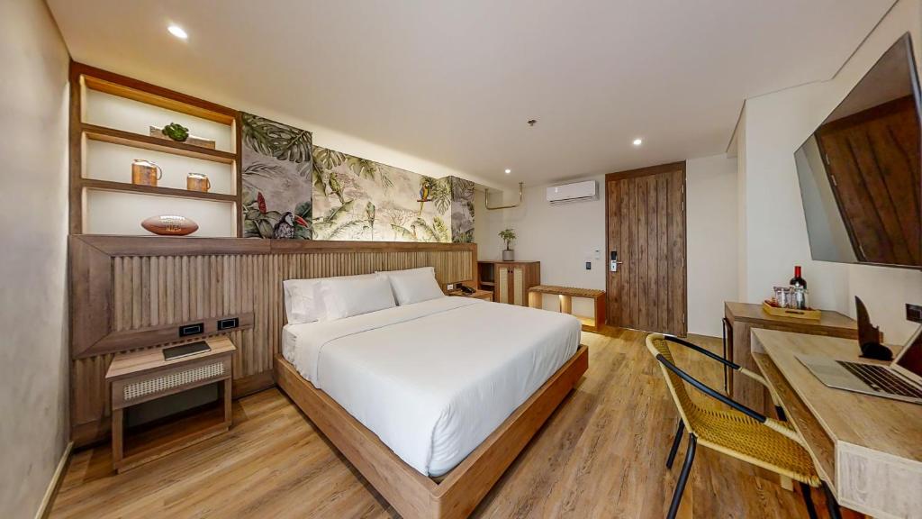 a bedroom with a bed and a desk with a laptop at Origen Hotel Boutique in Medellín