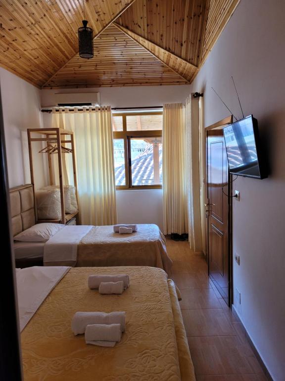 a bedroom with two beds and a flat screen tv at Nako Guest House bar&restaurants in Përmet