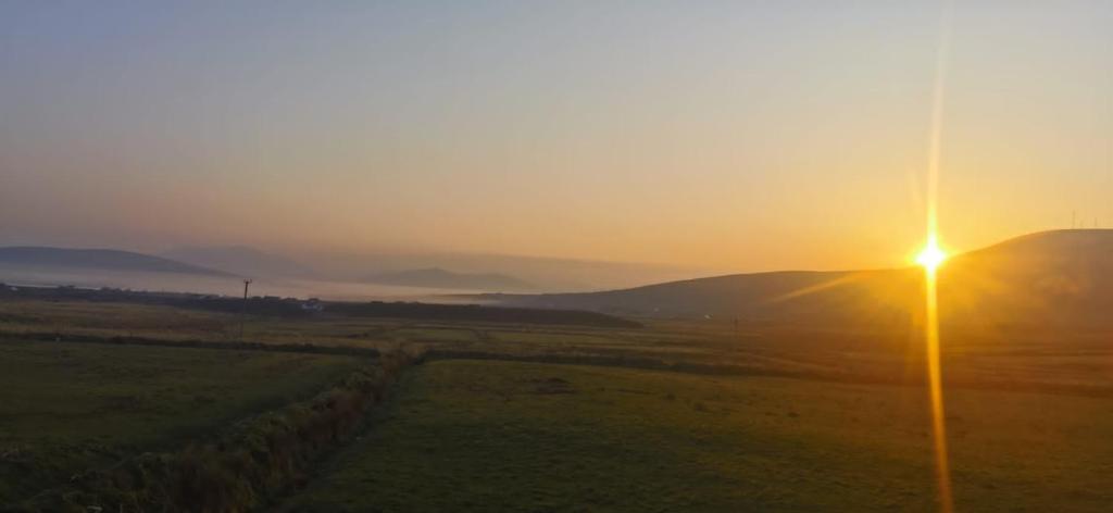 een zonsondergang boven een veld met een straatlicht bij Skellig View Harbour View Sunrise Apartment in Portmagee