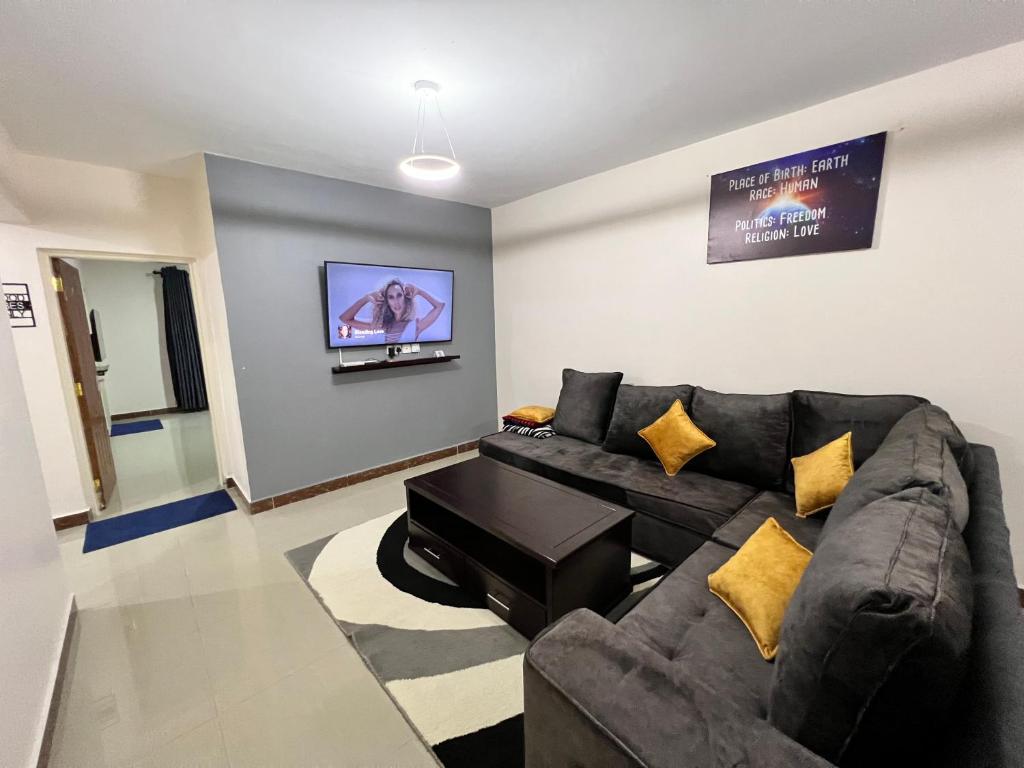 sala de estar con sofá negro y TV de pantalla plana en Champions Chill Suite en Eldoret