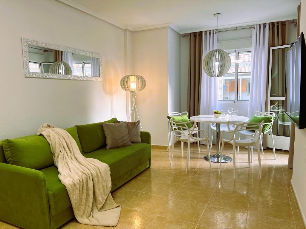 un soggiorno con divano verde e tavolo di Holiday Suite Fragata a Torrevieja