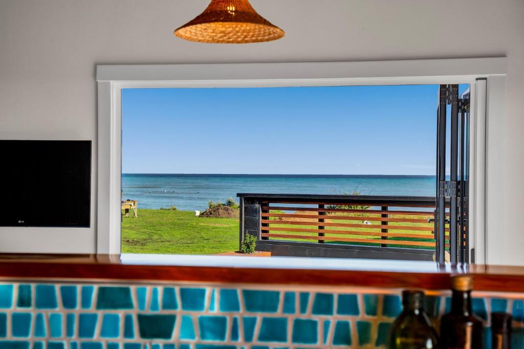 a window with a view of the ocean at Coastal Daze - New Plymouth Holiday Home in Okato
