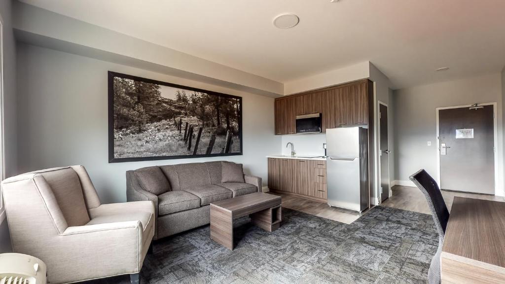 a living room with a couch and a chair and a refrigerator at Park Inn by Radisson Osoyoos in Osoyoos