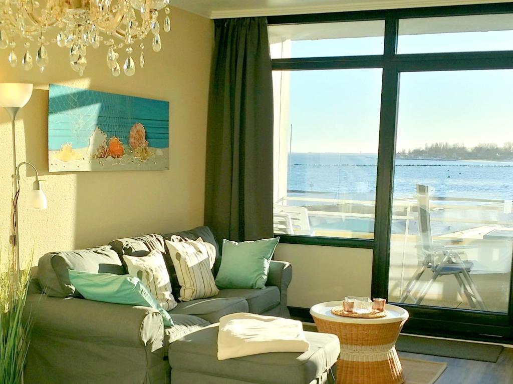 a living room with a couch and a large window at Fehmarn Burgtiefe Südstrand Meerblick Apartment MEERZEIT in Fehmarn