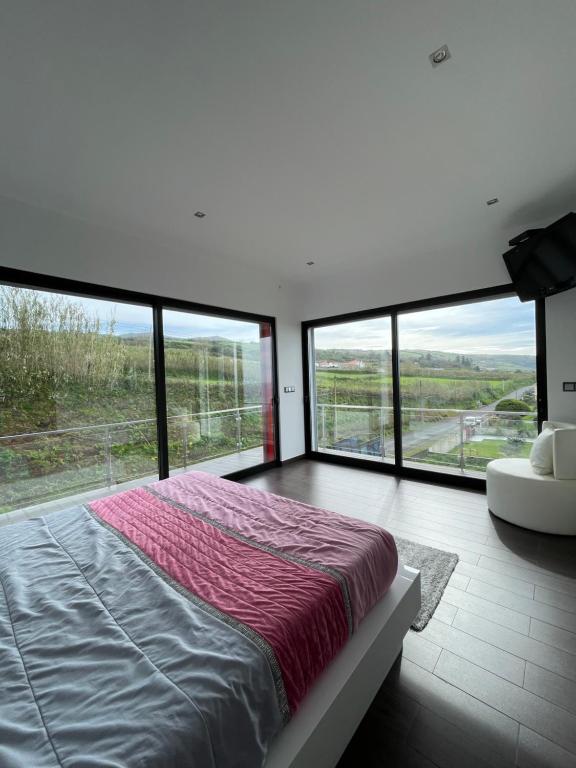 a bedroom with a large bed and large windows at Vivenda Luxuosa in Feteiras
