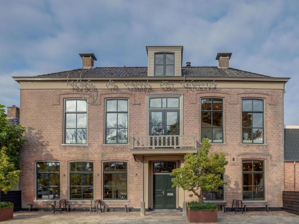 un edificio de ladrillo con ventanas y balcón en Group accommodation at unique location in Friesland, en Ternaard