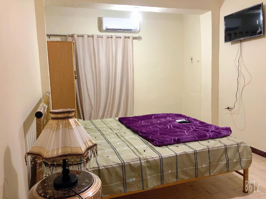 a bedroom with a bed with a purple blanket at Apartment near Abdeen Palace & Museum in Cairo