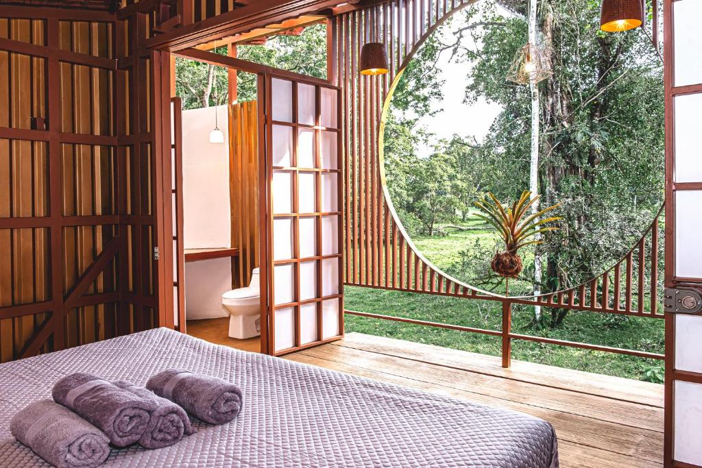 ein Schlafzimmer mit einem Bett und einem großen Fenster in der Unterkunft The Mimosas - Beautiful Unique Container Homes with Pool in Hone Creek