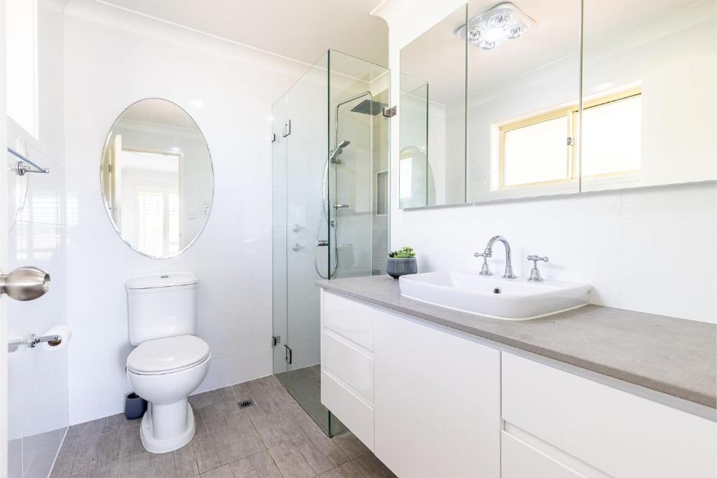 un bagno bianco con un water e un lavandino di Kanimbla House 15 Kanimbla Dr - air con, WiFi and pet friendly a Salamander Bay