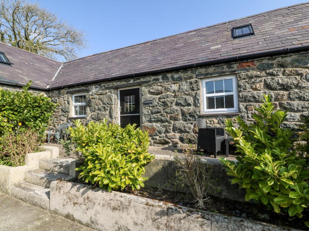 an old stone house with bushes in front of it at Bwthyn y Dderwen Oak Cottage in Llannor