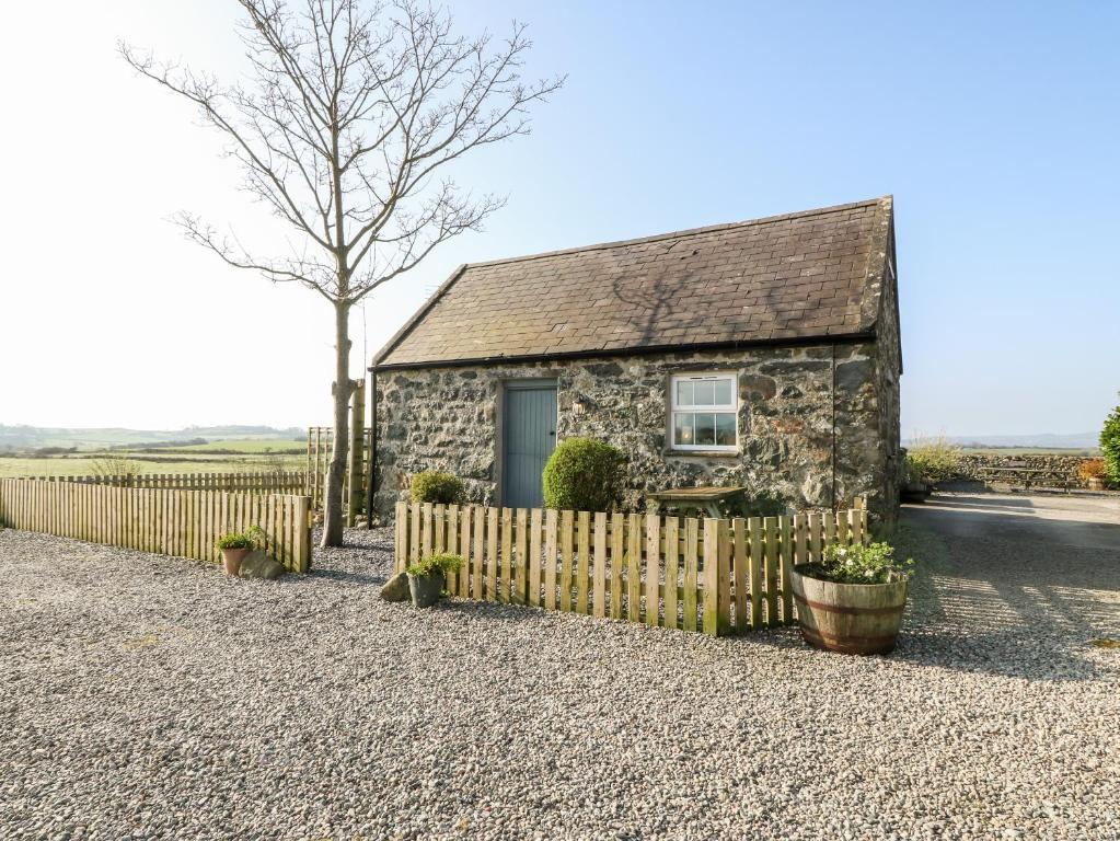 uma casa de pedra com uma cerca e uma árvore em Bwthyn Celyn Holly Cottage em Llannor