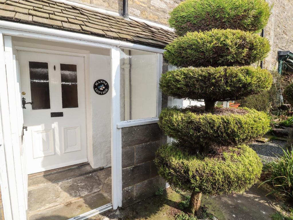 a door to a house with a bush next to it at Manna Cottage in Grassington