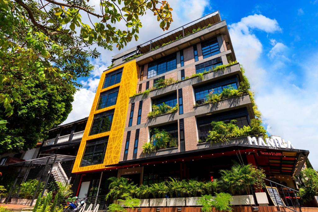 een hoog geel gebouw met planten erop bij Manila Hotel Boutique in Medellín