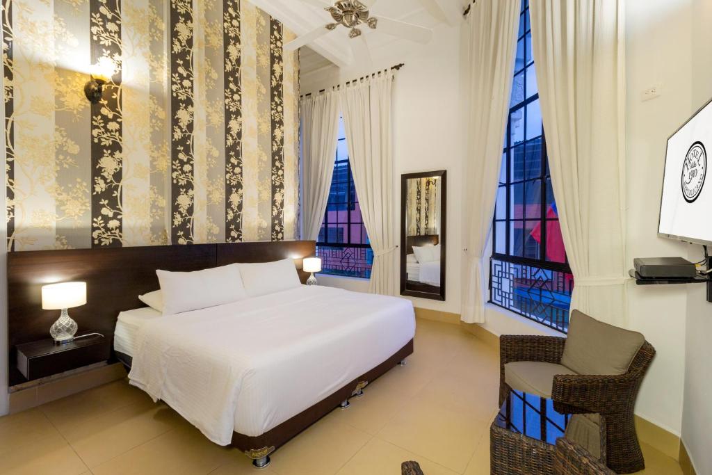 - une chambre avec un grand lit blanc et une chaise dans l'établissement Hotel Republicano 1910, à Girardot