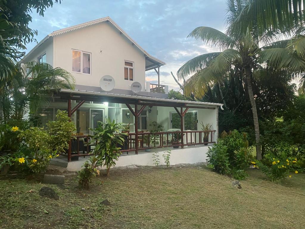 ein weißes Haus mit einem Balkon und Palmen in der Unterkunft Tigraviers Bed & Breakfast in Rodrigues Island