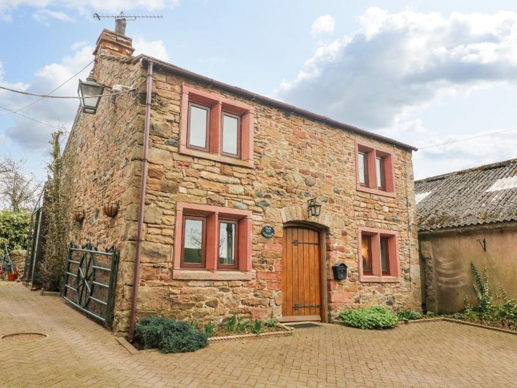 an old stone house with a wooden door at Elm Cottage in Warcop