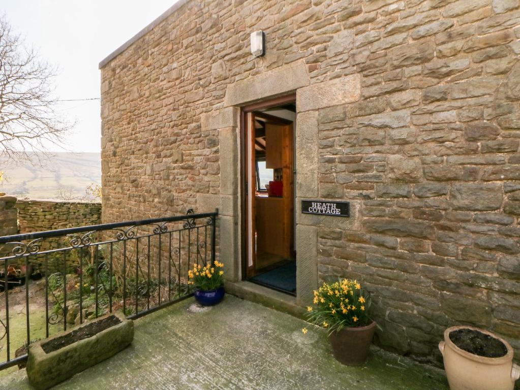 un edificio de ladrillo con puerta y balcón en Heath Cottage, en Edale