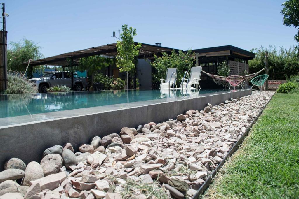 a swimming pool with chairs and rocks around it at Refugio Padma in Chacras de Coria