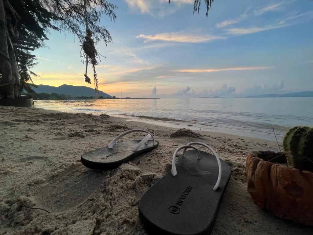 two pairs of flip flops sitting on the beach at Phangan Dream box in Baan Tai