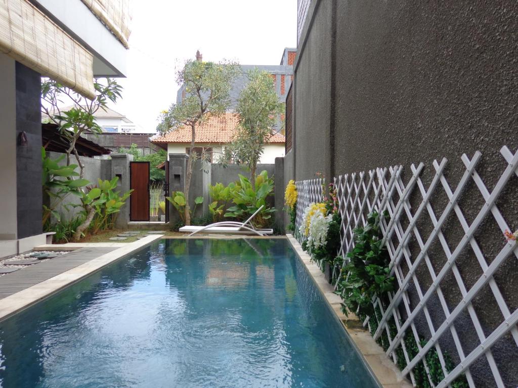 a swimming pool in a yard next to a building at Villa Lovecho in Canggu