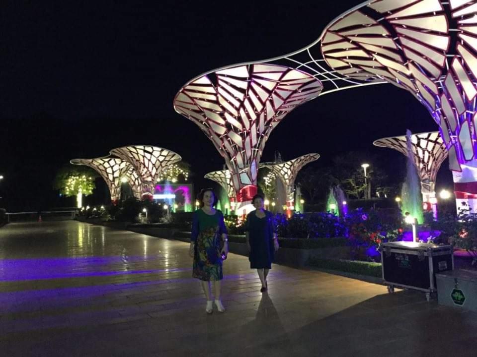 dos mujeres de pie frente a un edificio iluminado por la noche en Oceanami Resort & Beach Club, en Long Hai