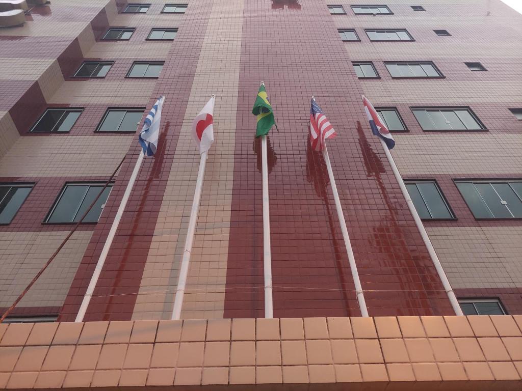 um edifício alto com bandeiras à frente em LUXOR VEROLME HOTEL em Angra dos Reis