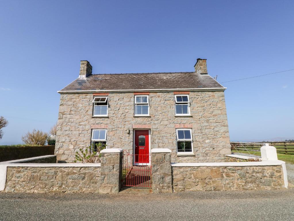 a stone house with a red door on a street at Bank House Farm in Croes-Gôch