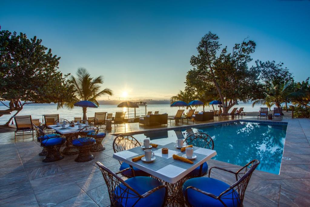 a resort with a pool and tables and chairs at Mariposa Belize Beach Resort in Placencia Village