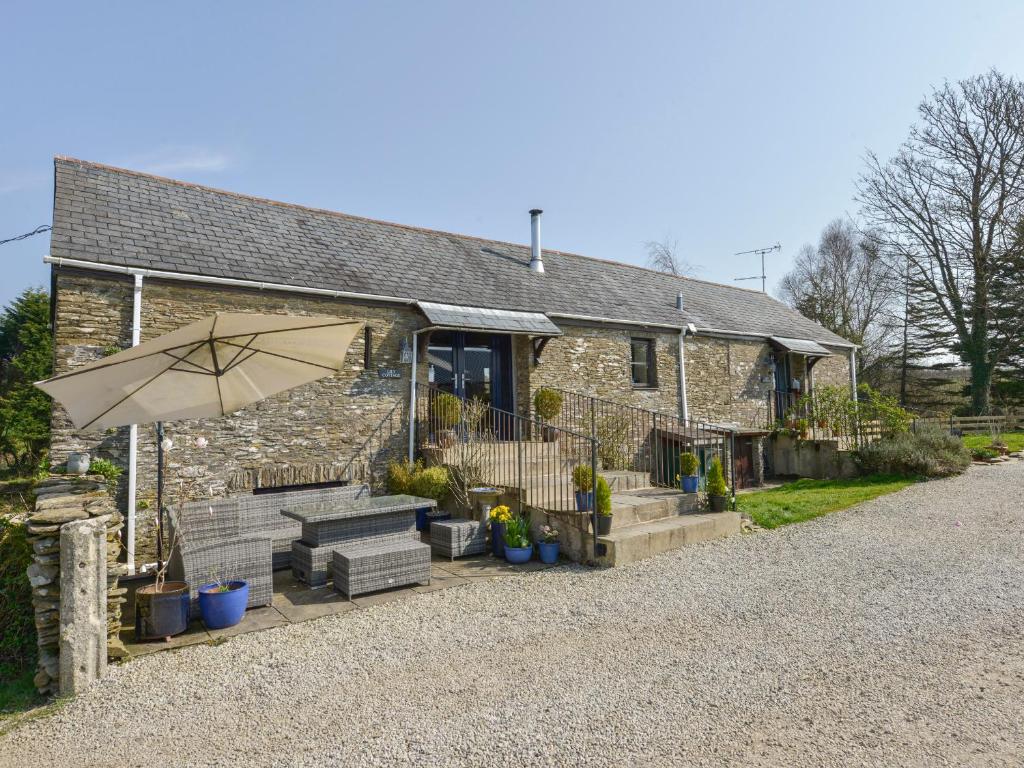 a stone house with an umbrella and a bench at Lily Cottage in Looe