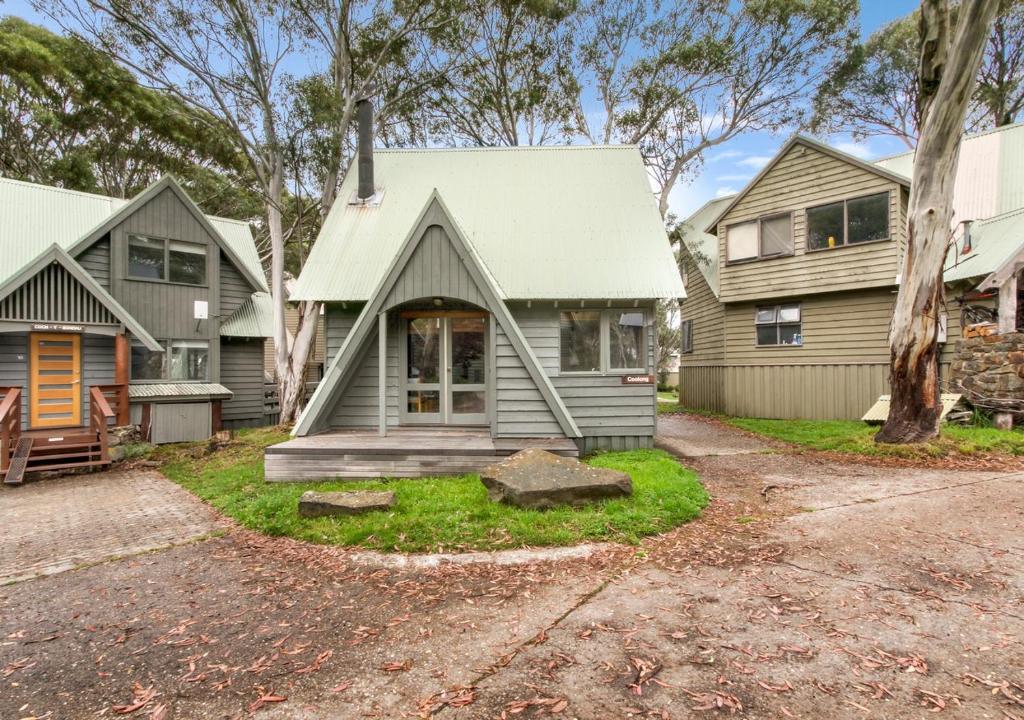 a gray house with a porch and a tree at Coolong in Dinner Plain
